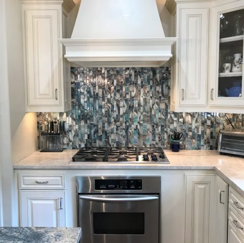 Kitchen range wall with a mosaic glass backsplash and wall oven