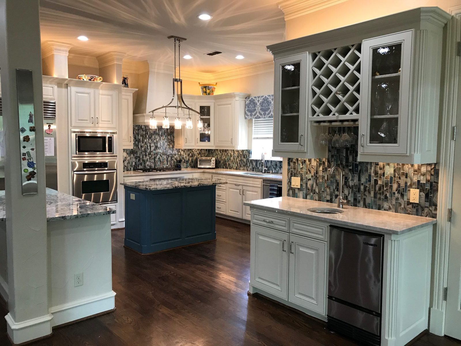 White kitchen with a blue island and mosaic backsplash in Dallas