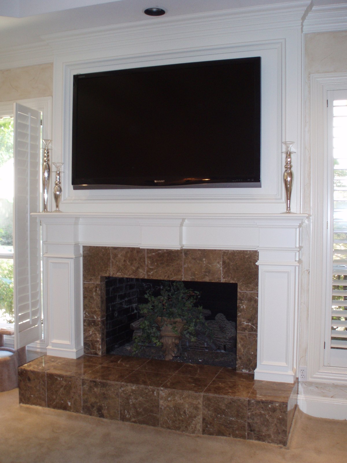 The same fireplace refaced in white painted panelling with a stone tile surround and a wall-mounted television