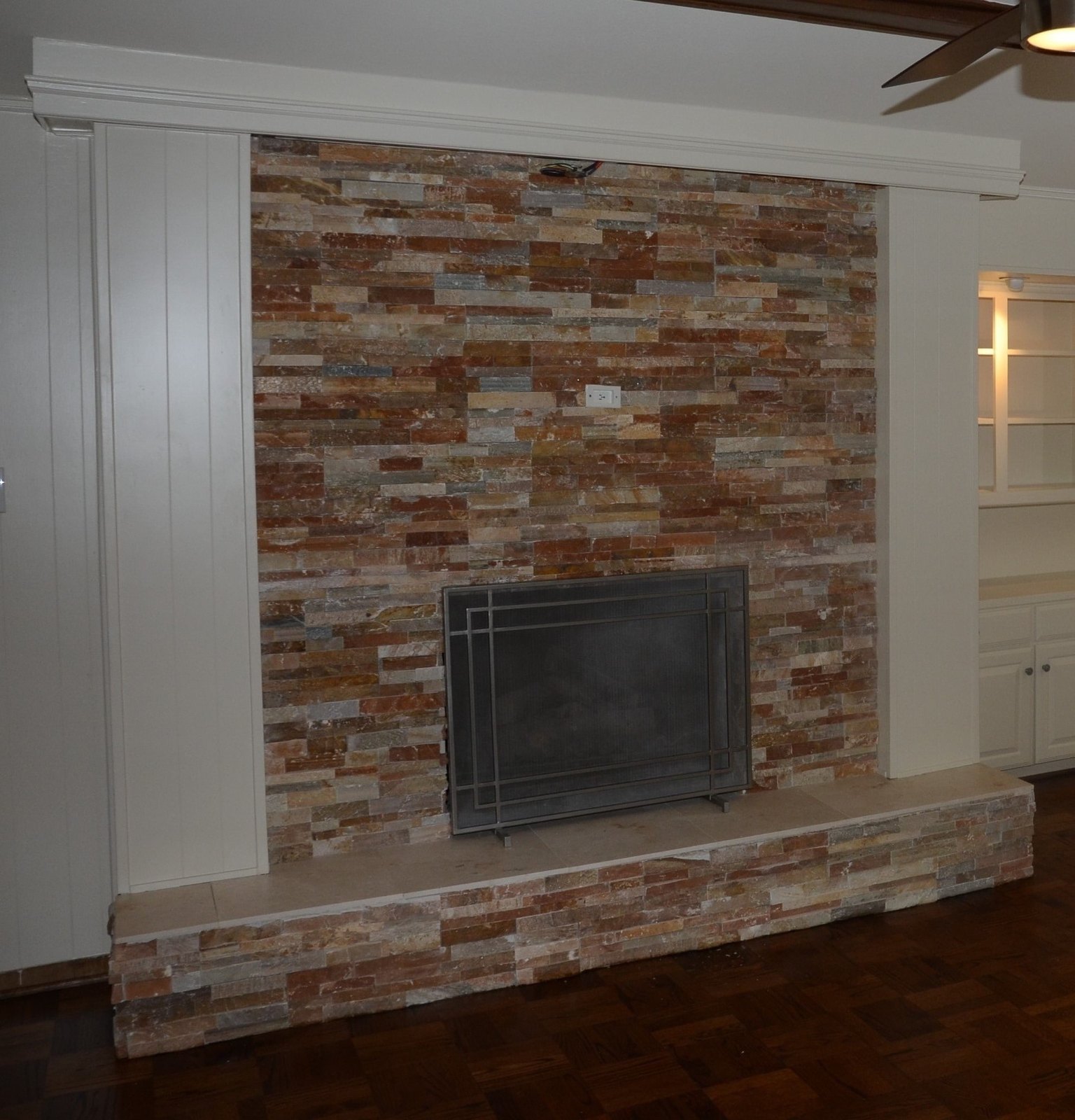 The same wall resurfaced in light stacked stone from floor to ceiling with a linear firebox
