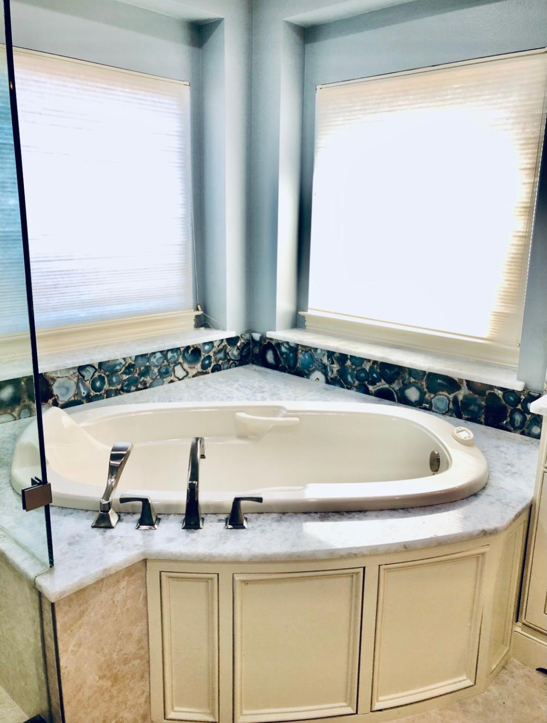 Corner soaking tub with an agate mosaic surround beneath the windows