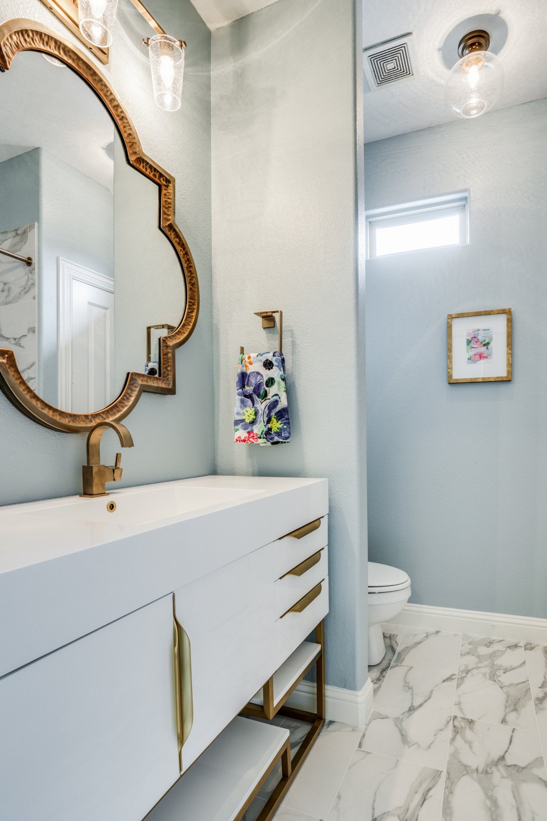 Modern master bathroom with a floating stone vanity and a gold-framed mirror