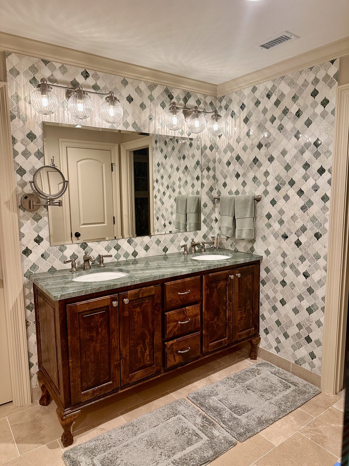 Wood vanity against a full wall of diamond mosaic tile