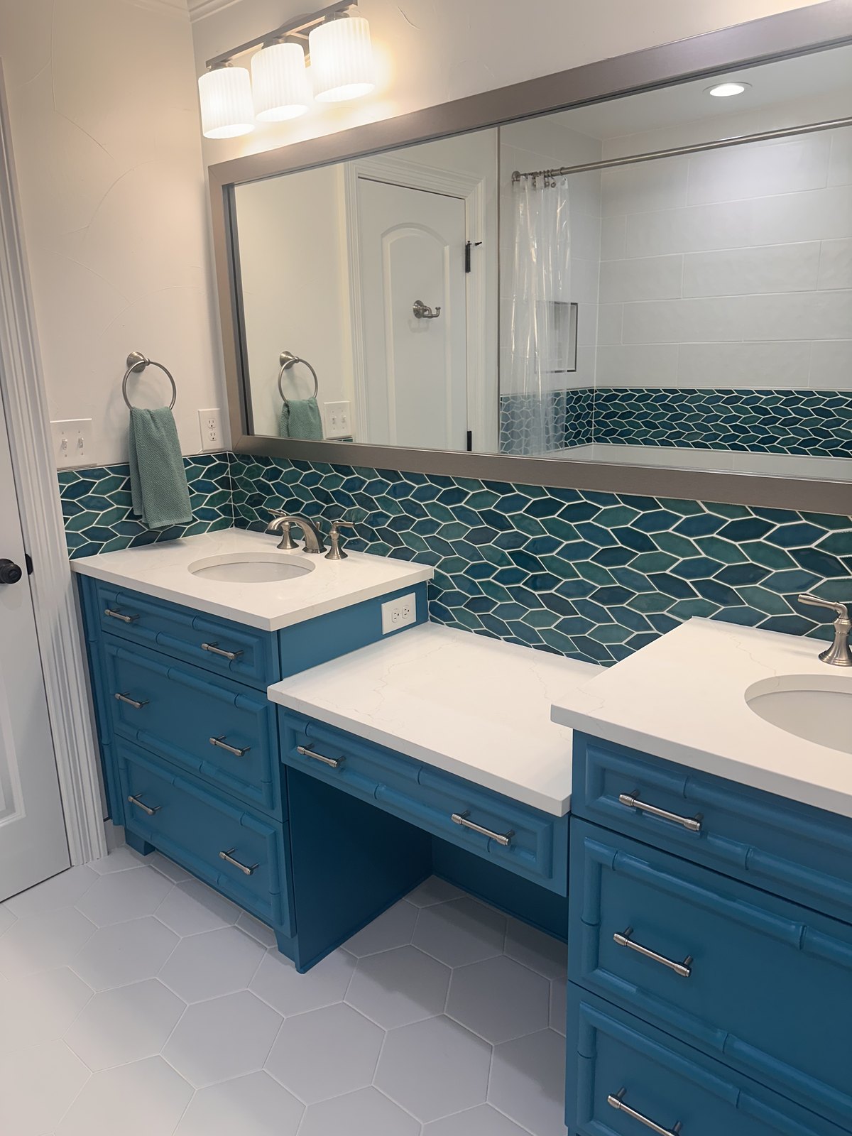 Double vanity in teal with marble counters and fan-tile backsplash