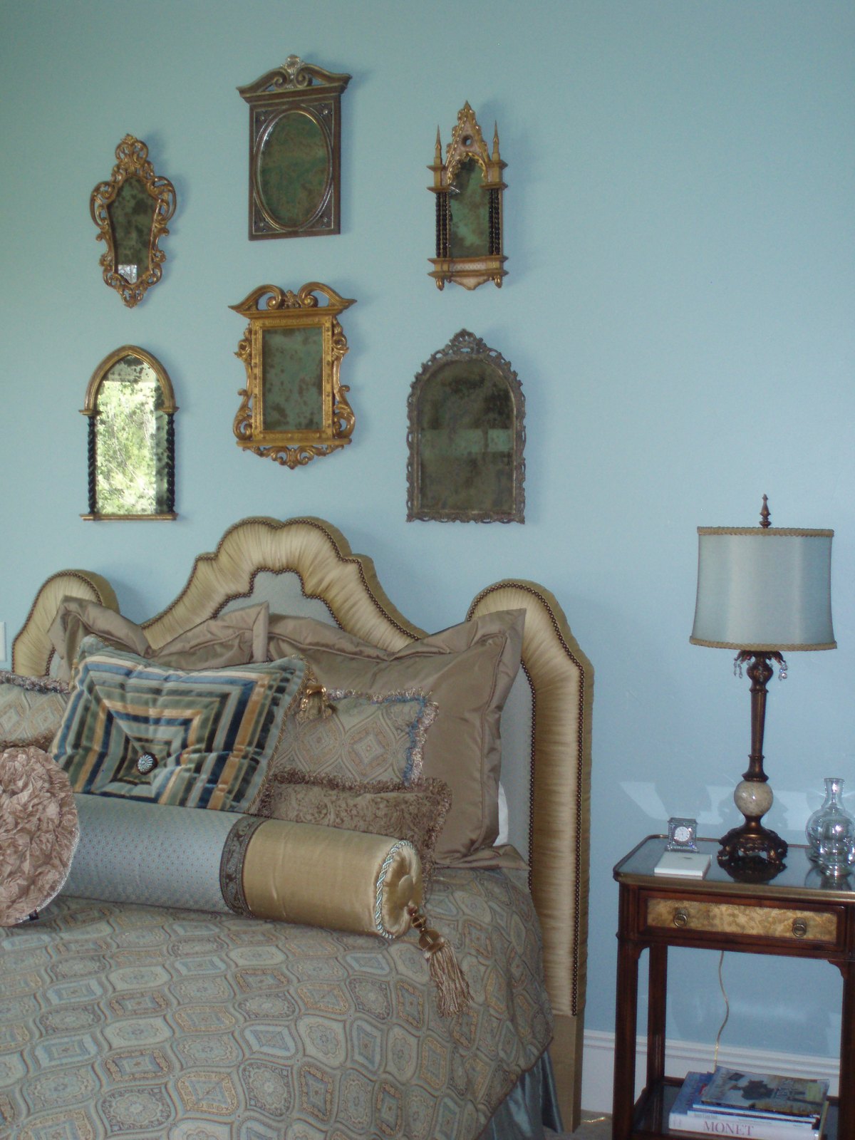 Bedroom with antique mirrors arranged above the bed