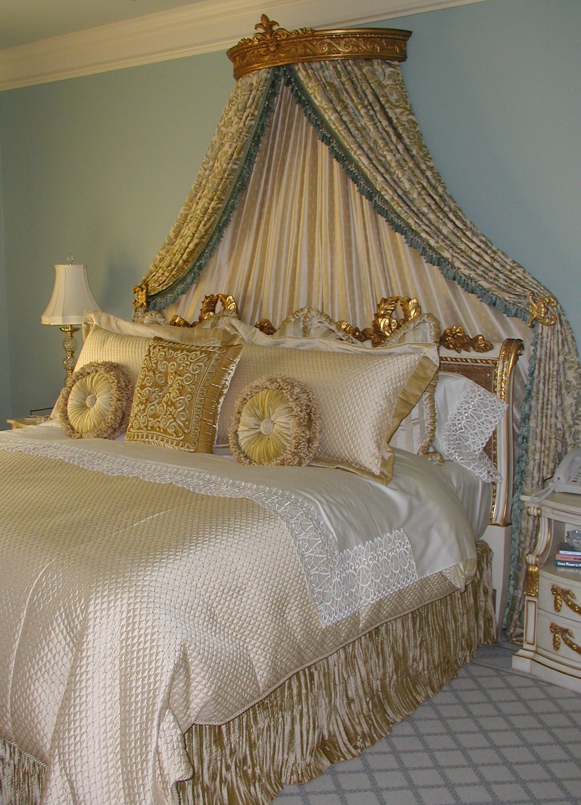 Bed crowned with a gilded corona and cascading drapery