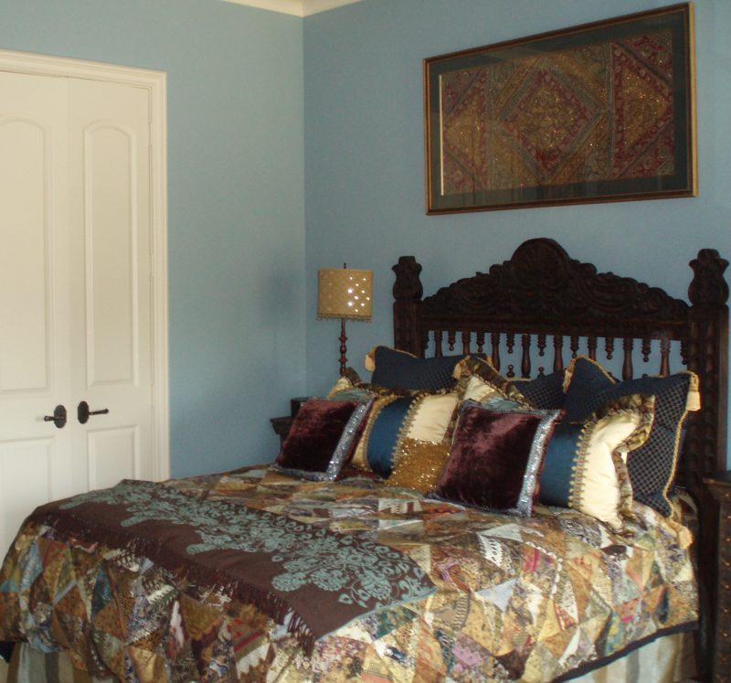Bedroom with a carved headboard and layered quilted textiles