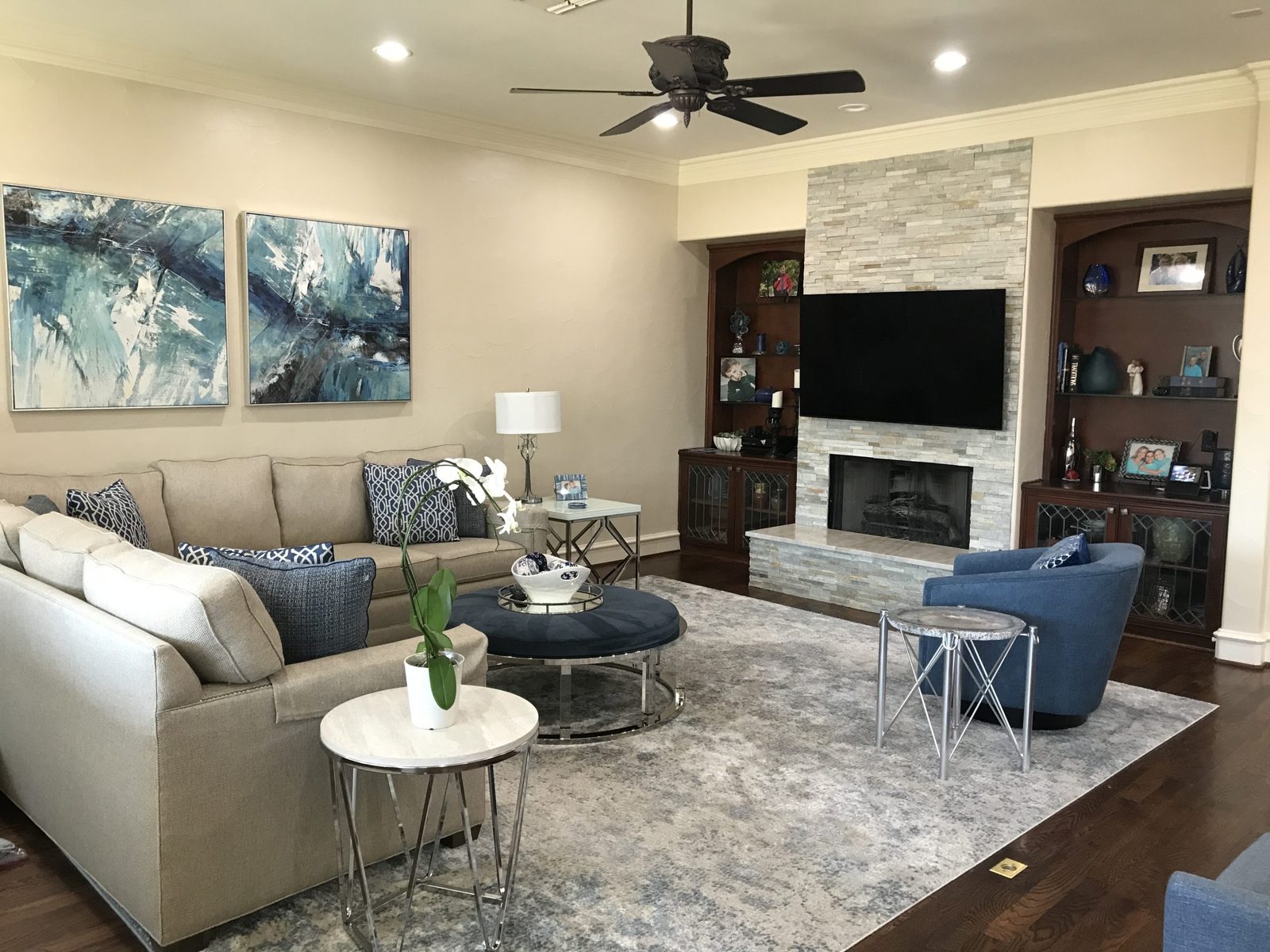 Family room with stone fireplace and blue accents designed by Chateau Concepts in Dallas