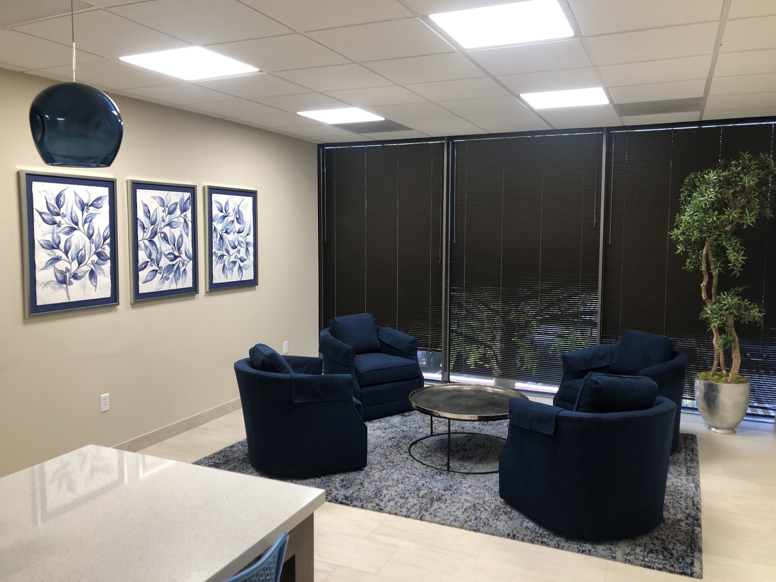 Tenant lounge with navy swivel chairs, botanical prints and a blue glass pendant