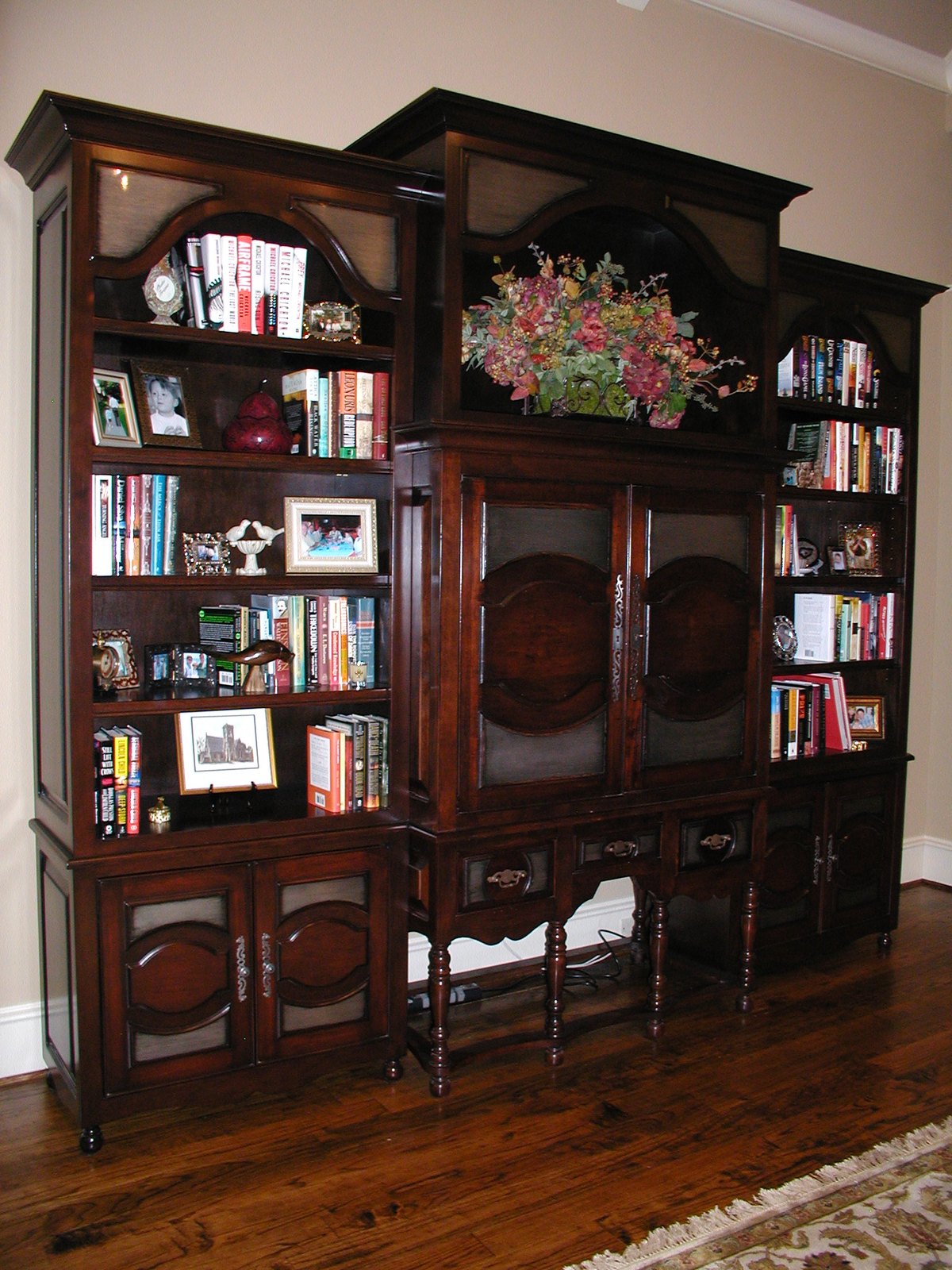 Carved dark-wood television cabinet with metal inlays flanked by bookshelves