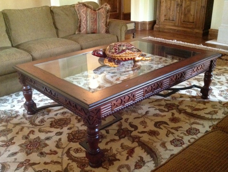 Custom carved cocktail table with an inset glass top