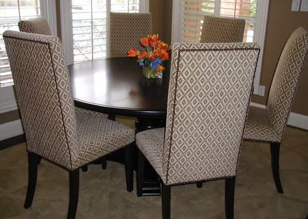 Dining chairs upholstered in a patterned neutral fabric around a dark wood table