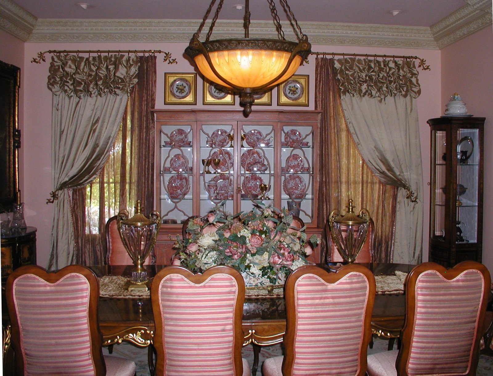 Formal dining room with rose striped chairs and a rose-painted china cabinet