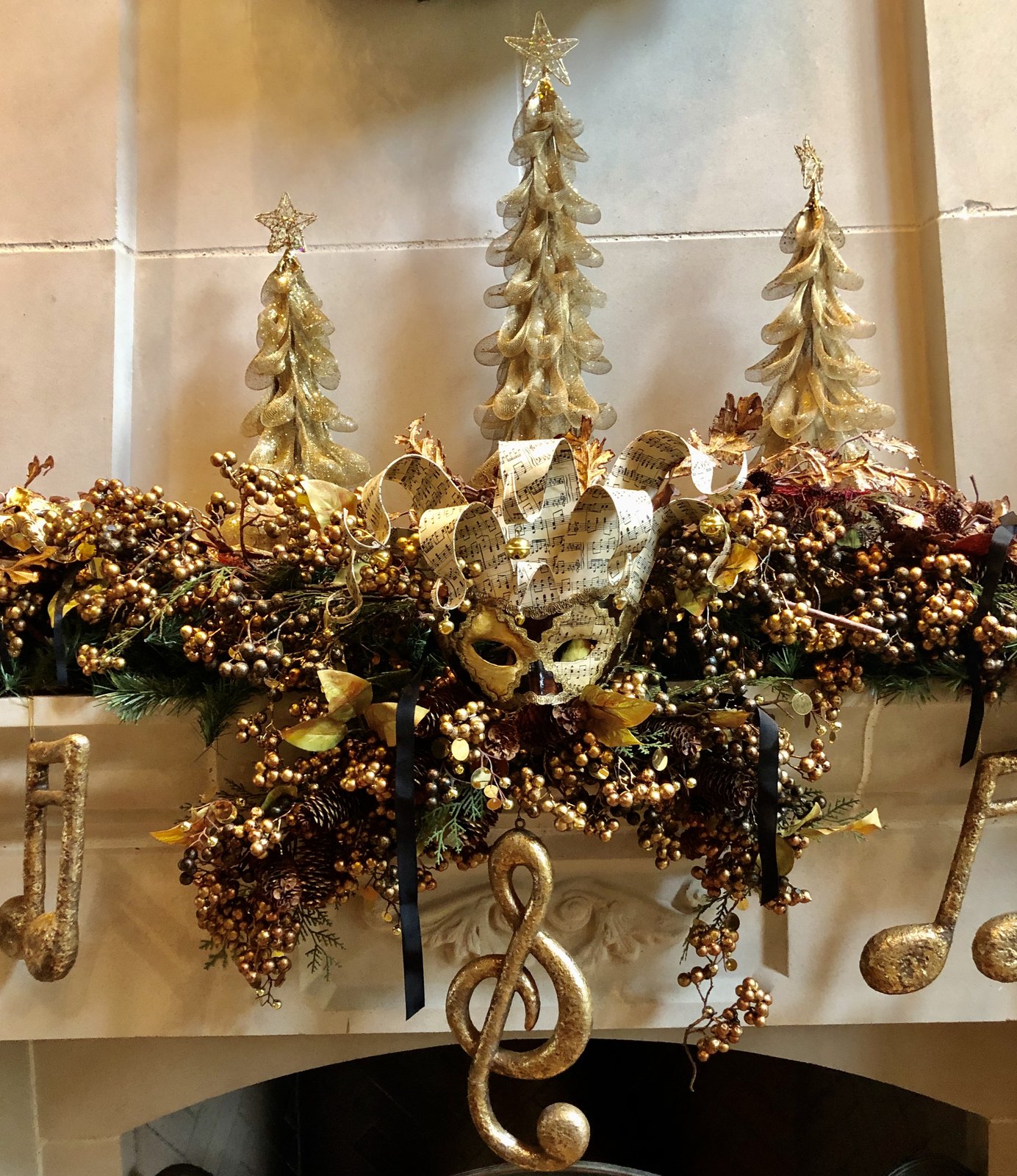 Gold garland with ribbon, ornaments and a treble clef ornament along a mantel