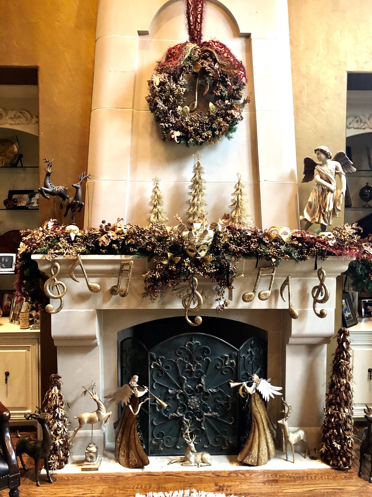 Mantel garland of gilded trees, ribbon and musical note ornaments above a fireplace