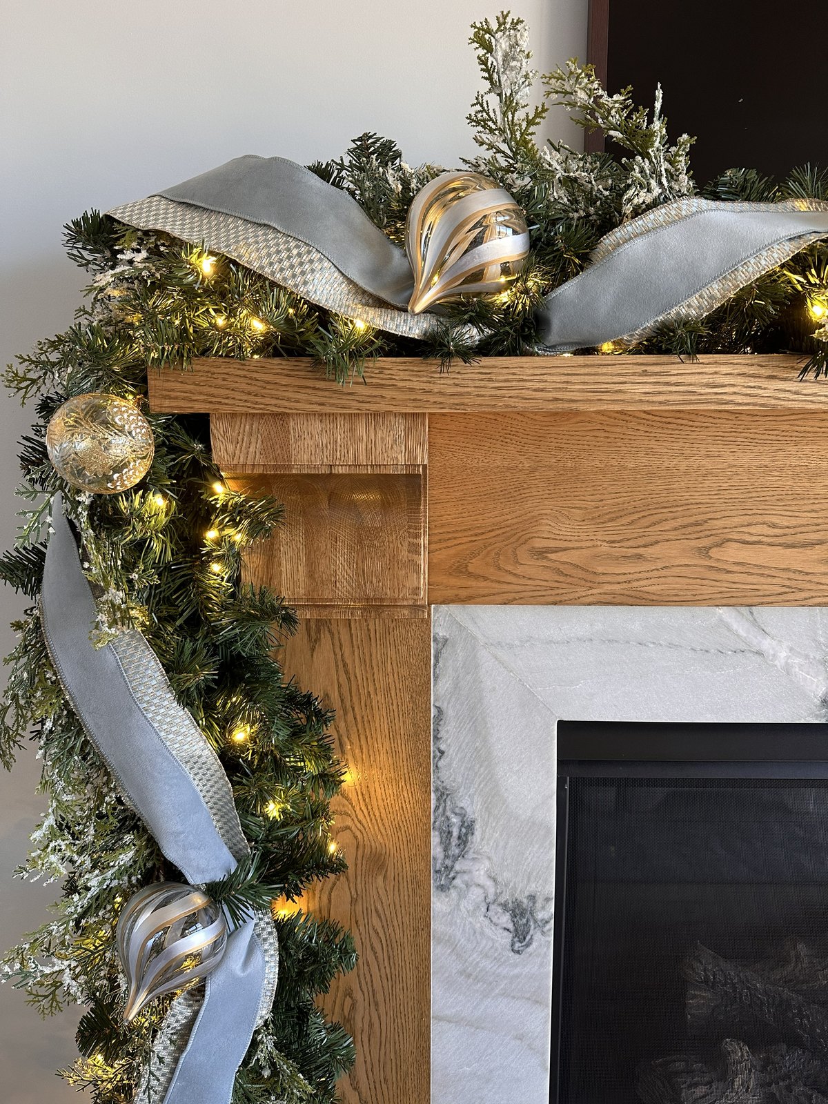 Mantel garland in silver and blue with ribbon, baubles and lights on an oak beam