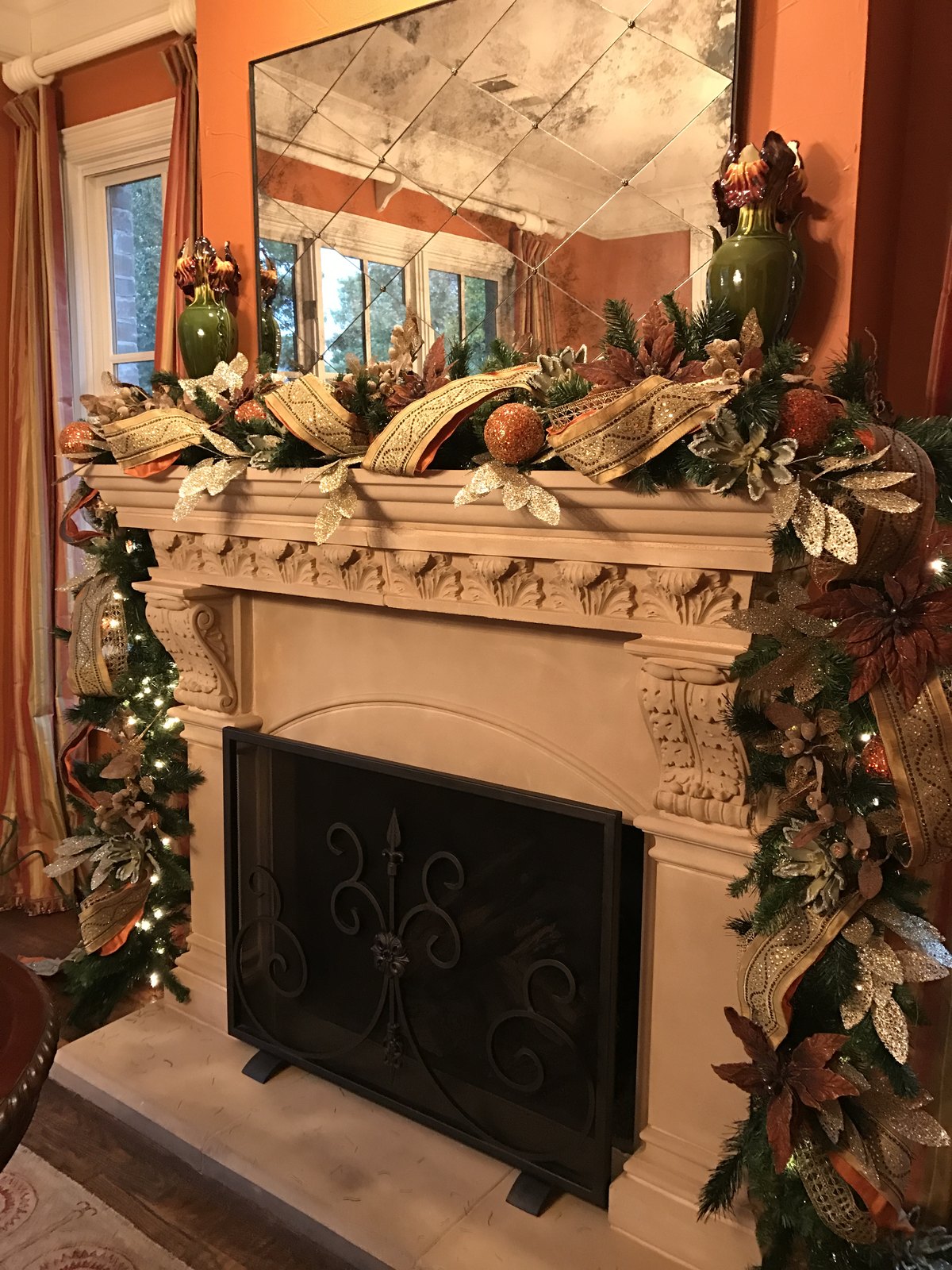 Carved stone fireplace framed by a full evergreen garland in a warm terracotta room