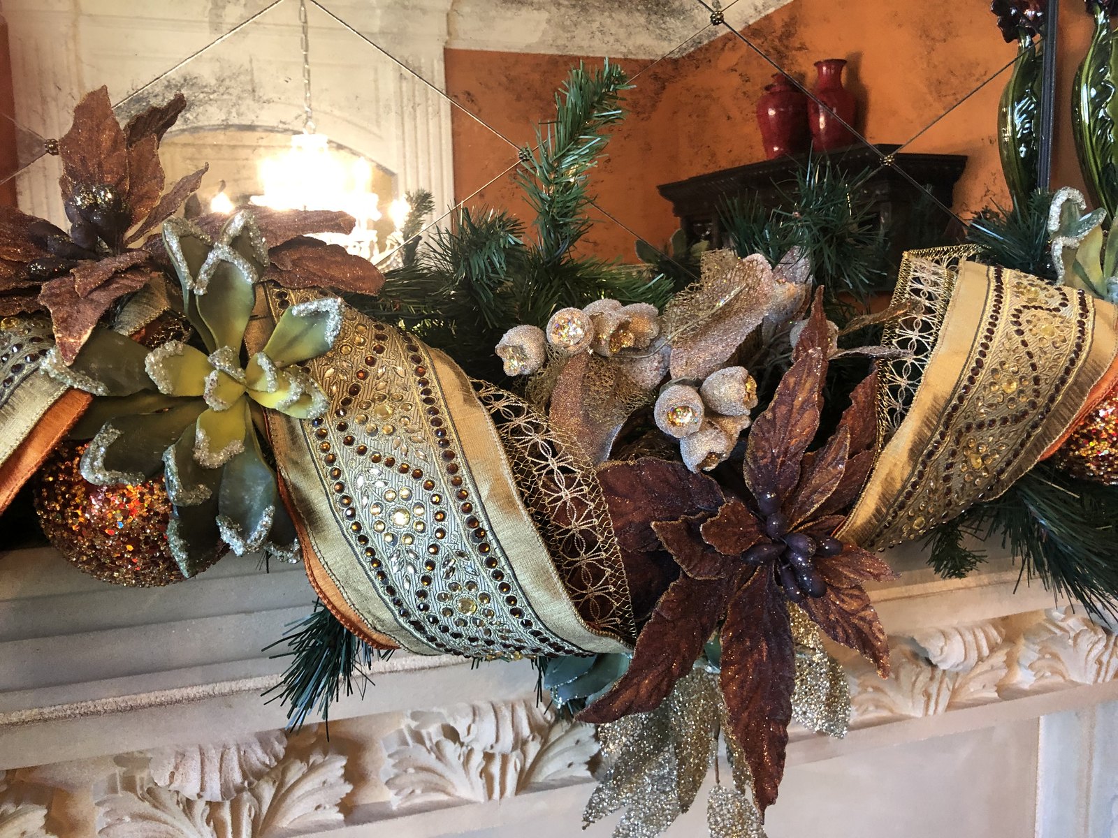 Mantel arrangement of poinsettias, berries and succulents in teal, copper and cream