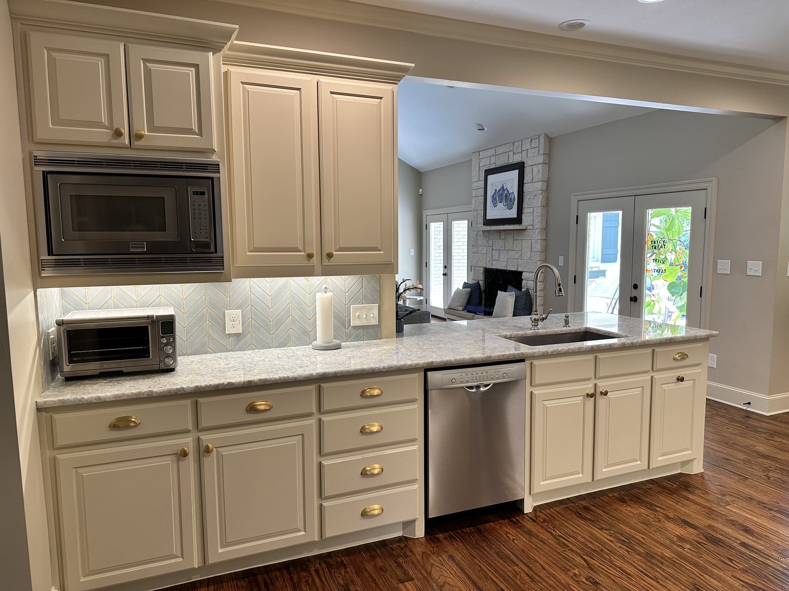 Kitchen with glazed cream cabinetry, light stone counters and hardwood floors