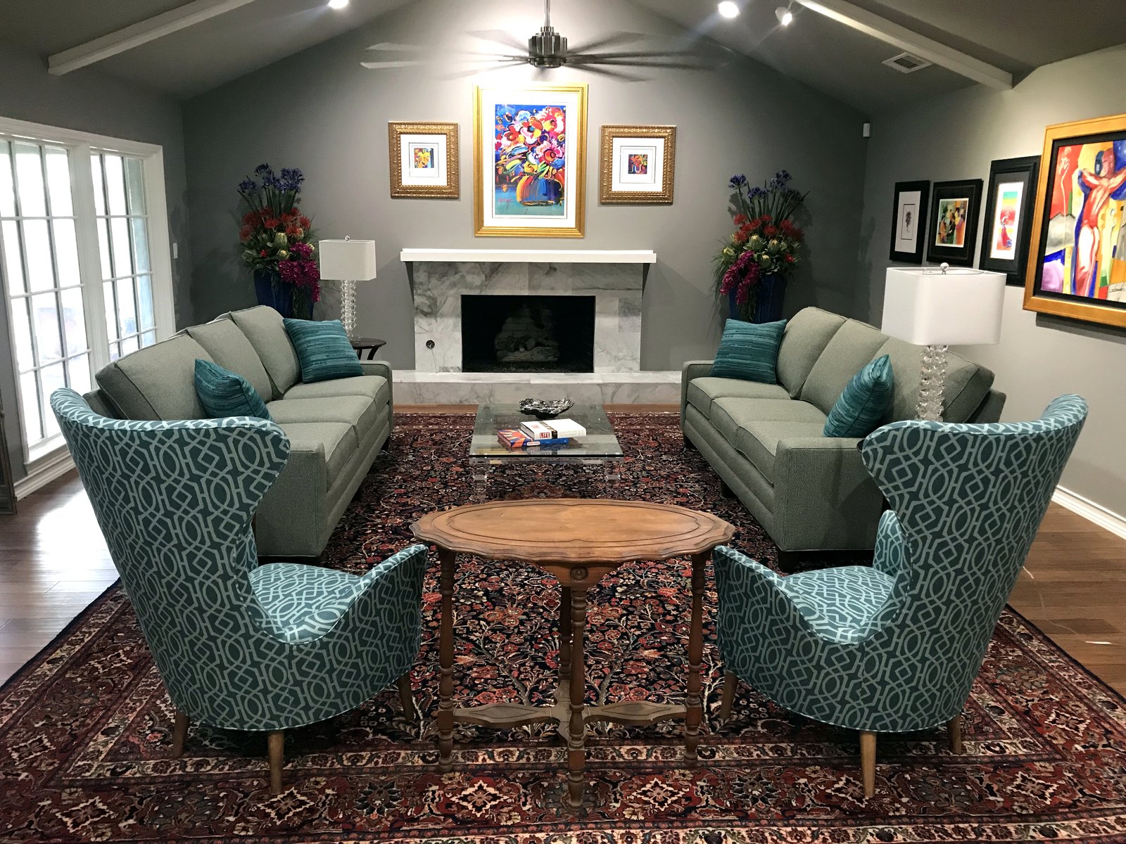Family room with teal wing chairs, a white fireplace and bold framed art