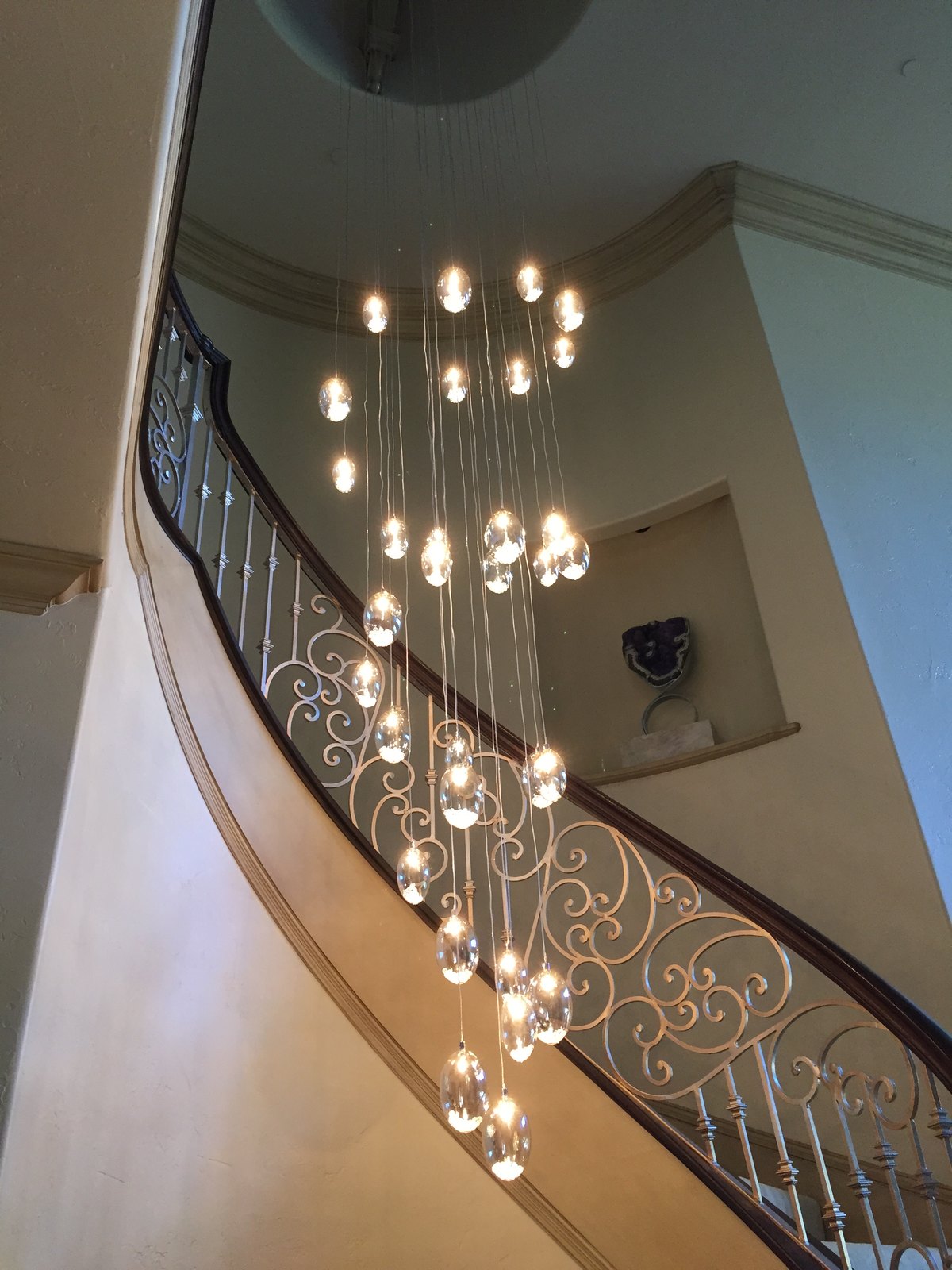Curved staircase with a cascading crystal chandelier in a Park Cities home