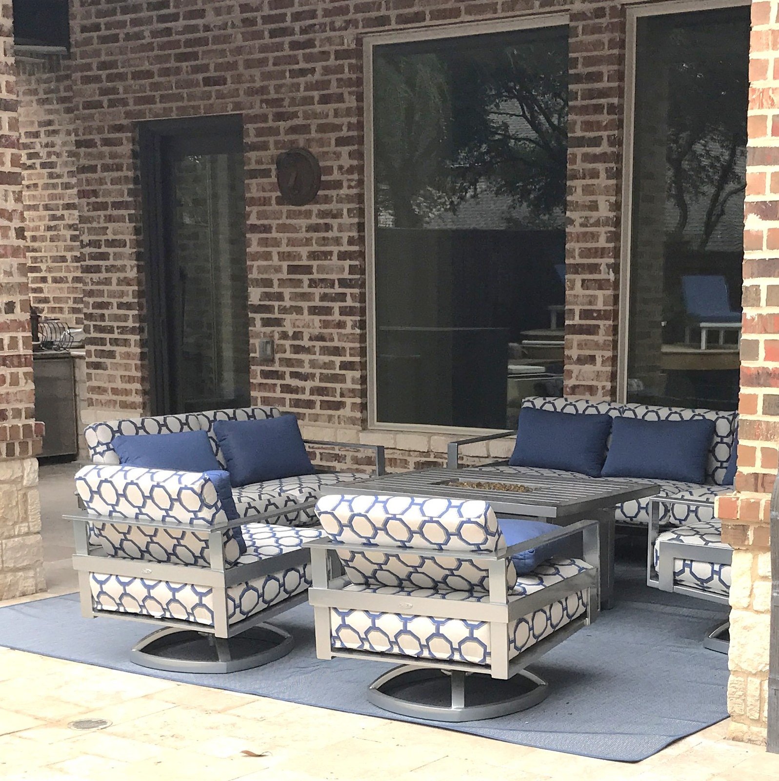 Covered patio with blue and white patterned outdoor seating against a brick wall