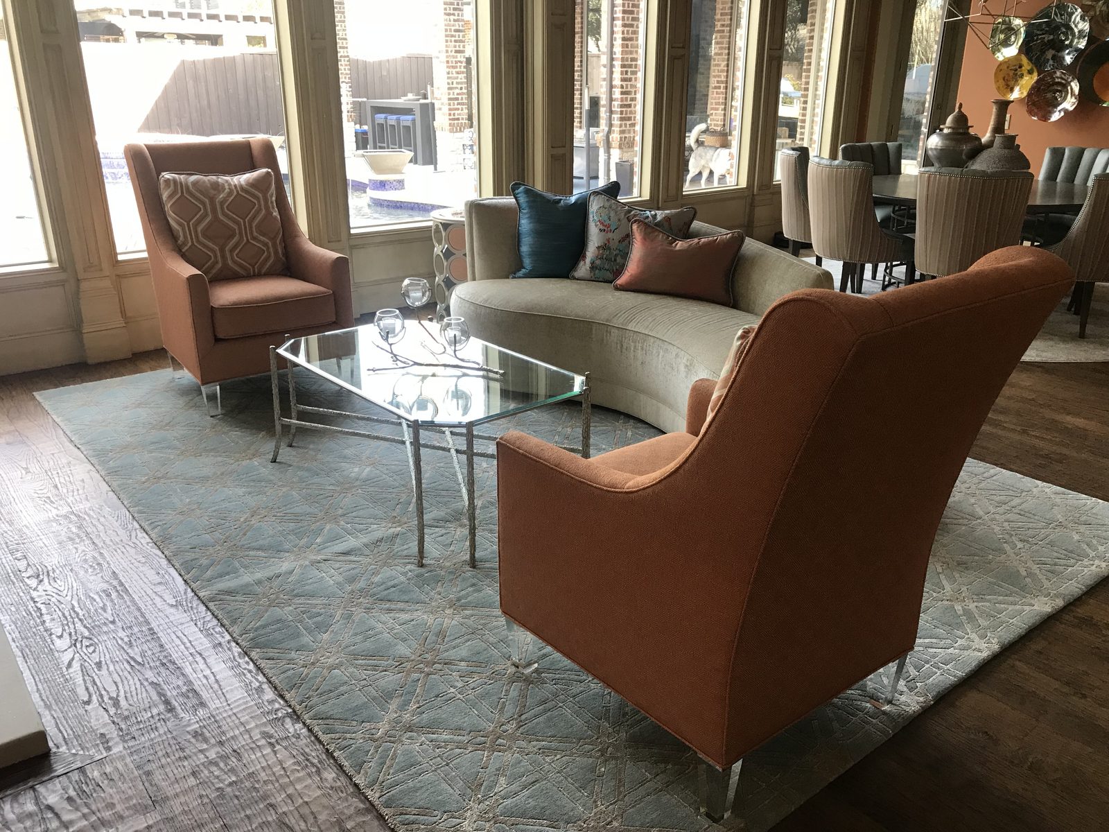 Living room with rust accent chairs, a glass coffee table and a layered rug