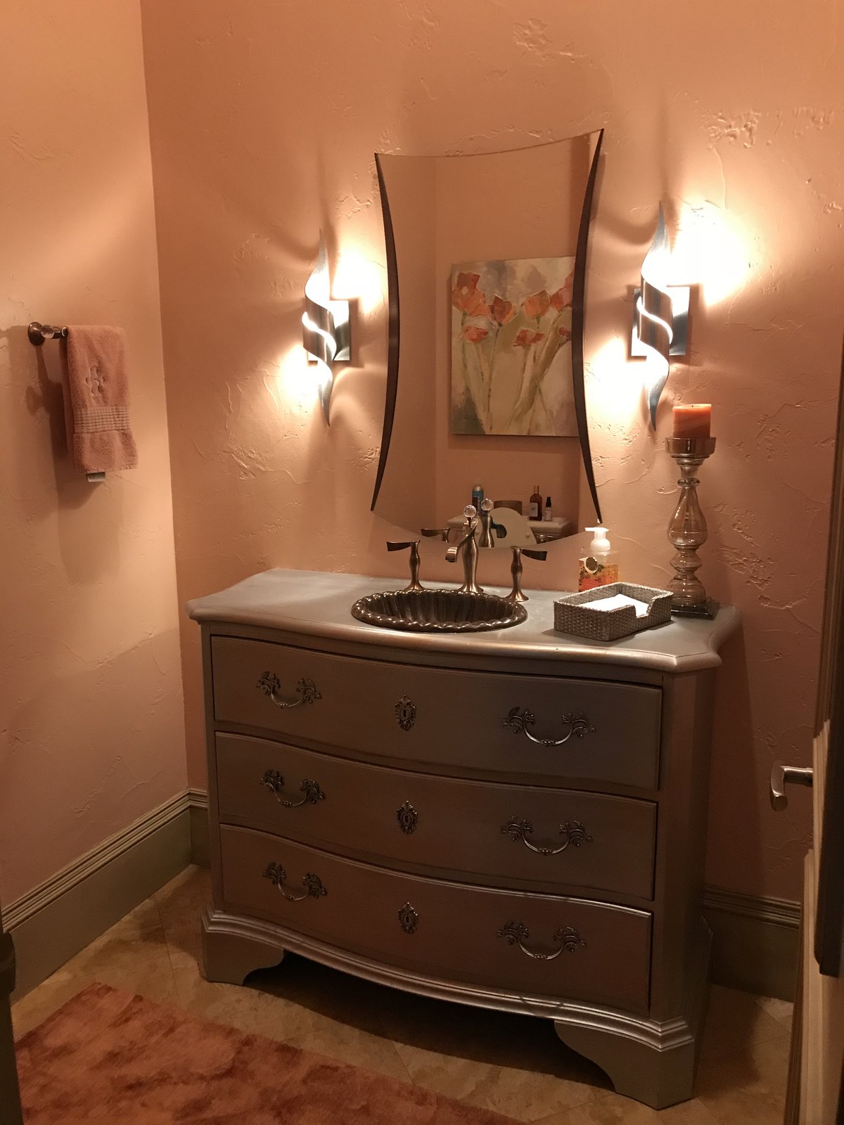 Powder room with an antique chest vanity and candle sconces