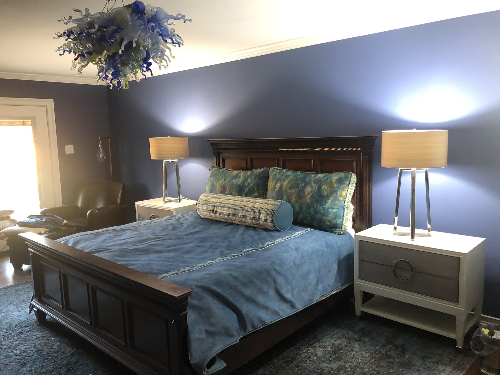 Master bedroom in blue with a carved wood bed and a blown-glass chandelier